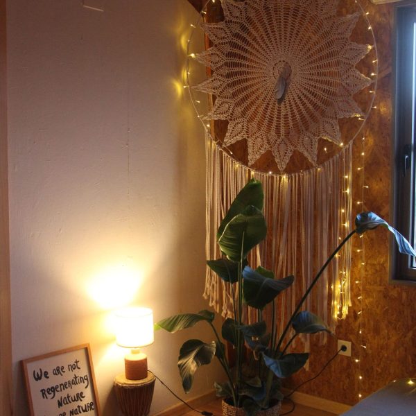 Canto intimista com iluminação quente, elementos naturais e artesanais como mandala de crochê e plantas, promovendo aconchego e reconexão.